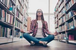 college student meditating in library